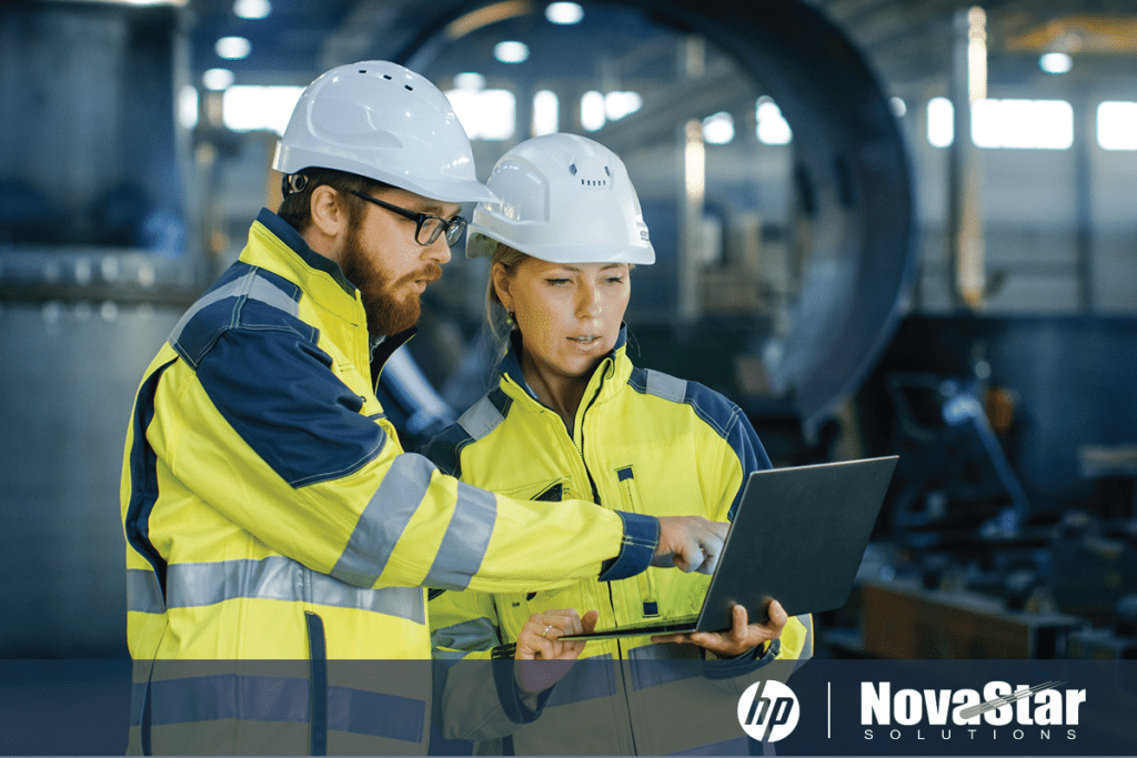 Man and woman in reflective jackets and hard hats look at an HP Zbook in an industrial setting